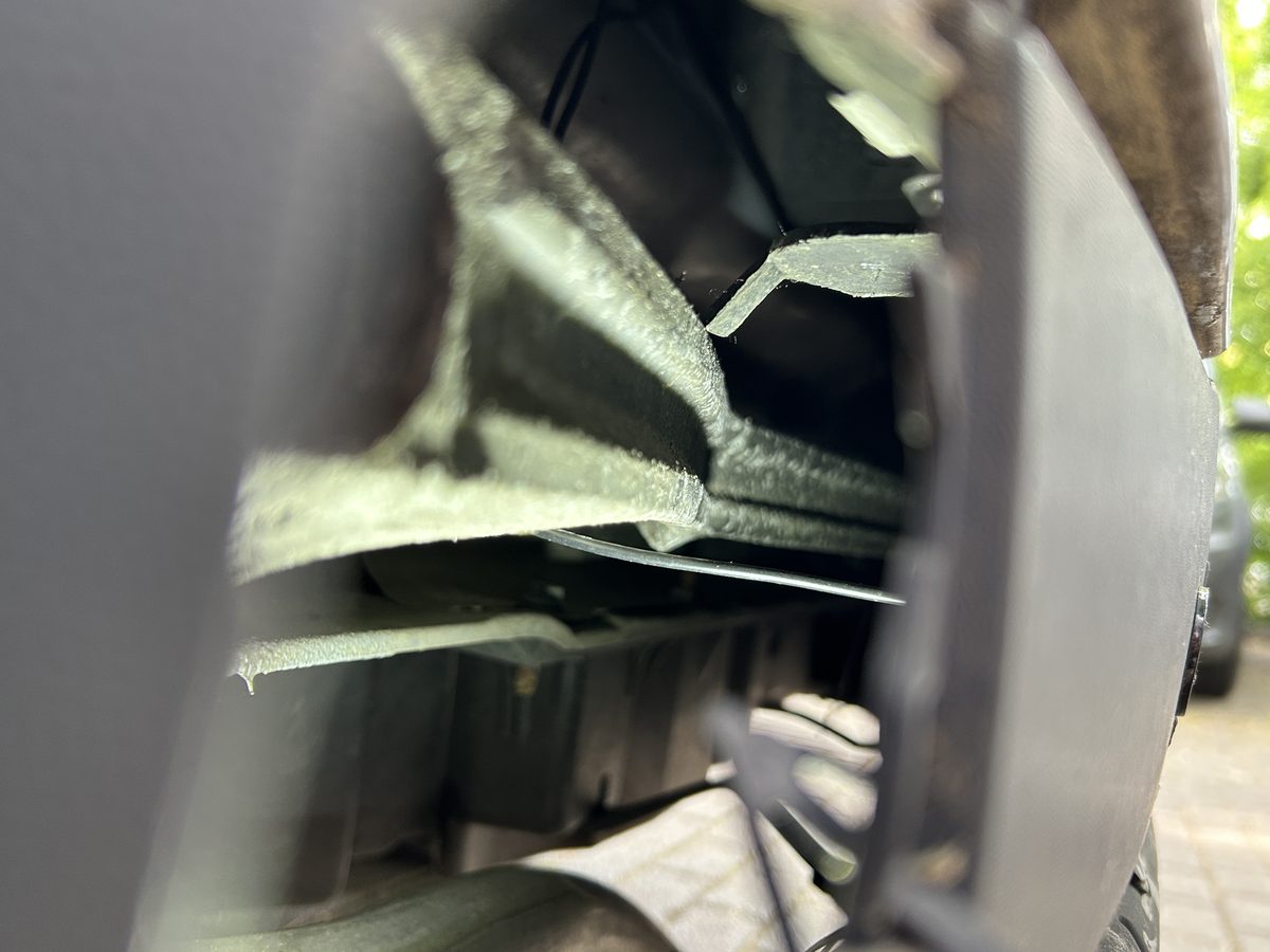 Aufgerissenes Blech mit herausgebrochener Trägeraufnahme hinter der Stoßfängerschale eines silbernen Renault Mégane, wirtschaftlicher Totalschaden